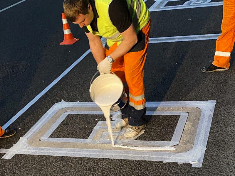 Процесс нанесения разметки на парковке для инвалидов с использованием трафаретов Процесс нанесения разметки на парковке для инвалидов с использованием трафаретов